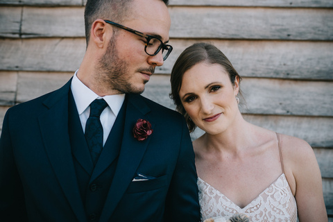 bride and groom portraits in front of rustic barn wall