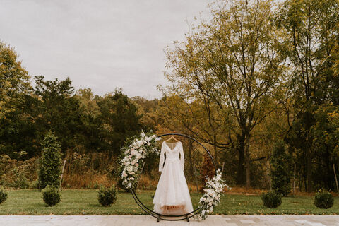 long sleeve lace wedding dress hanging on floral ring - 48 Fields Wedding Barn | Leesburg VA