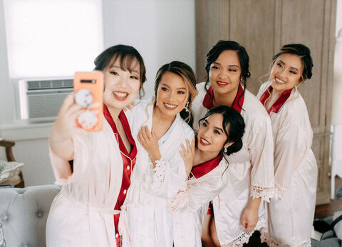 bride and bridesmaids selfie in matching red and white robes - 48 Fields Wedding Barn | Leesburg VA